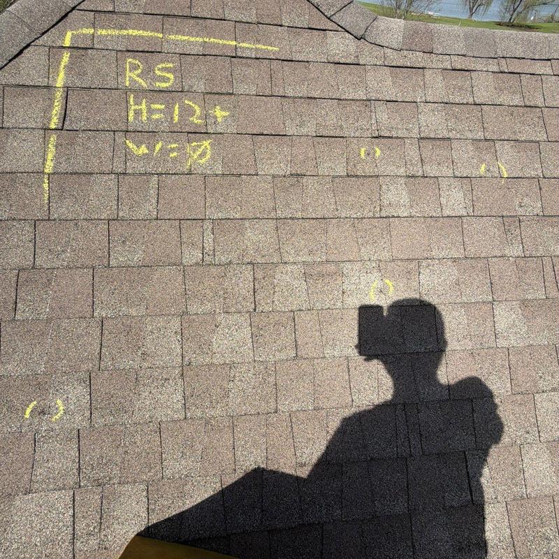 Asphalt shingles with hail damage markings on roof