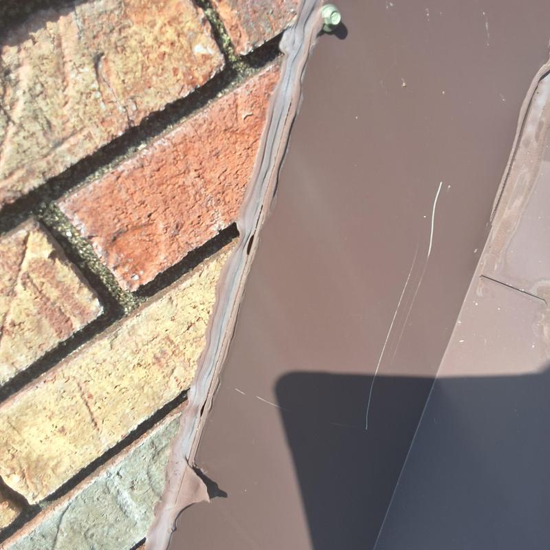 Chimney flashing with sealant applied on brick wall Chimney flashing with sealant applied on brick wall