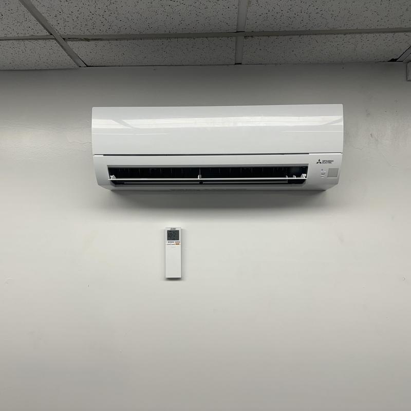 Mini split air conditioner with remote on office wall Mini split air conditioner with remote on office wall