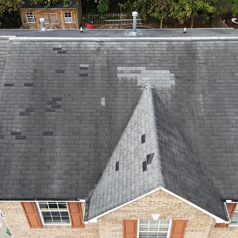 Asphalt shingle roof with damaged and patched areas Asphalt shingle roof with damaged and patched areas