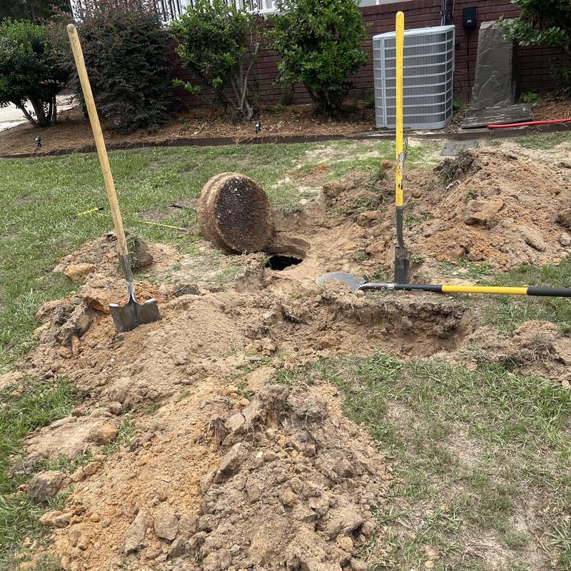 Mainline sewer excavation with shovels and removed cover Mainline sewer excavation with shovels and removed cover