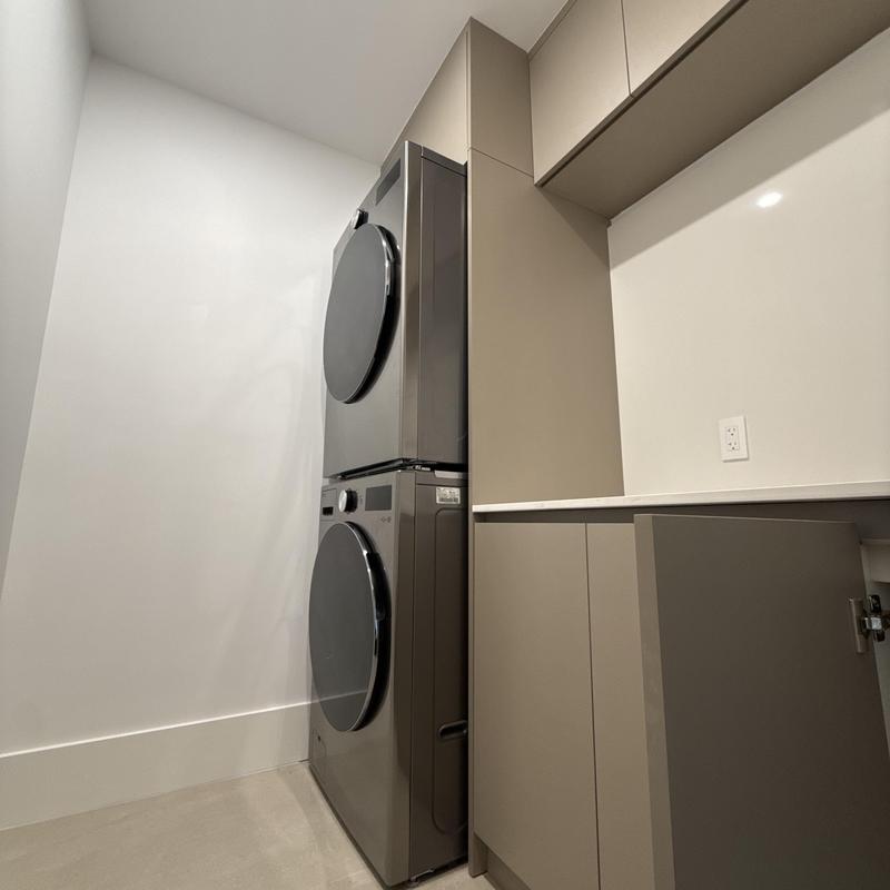 Stacked washer and dryer next to cabinetry cleanup Stacked washer and dryer next to cabinetry cleanup