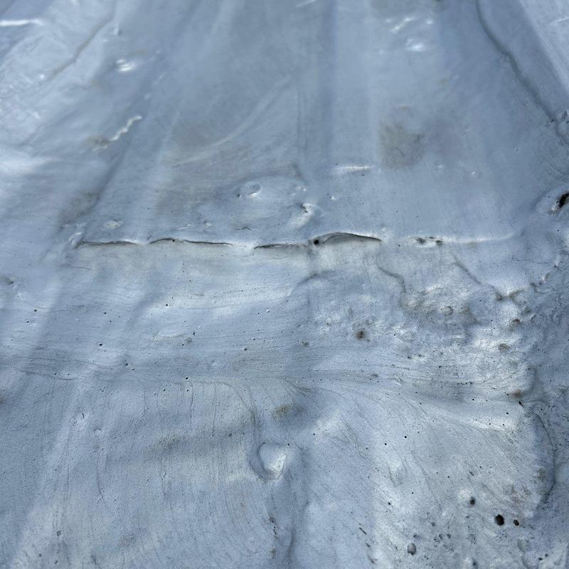 Metal roofing panel with hail damage dents and cracks