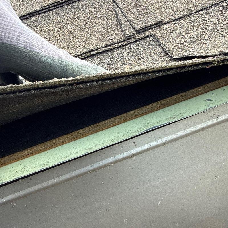 Asphalt shingle roof edge peeled up for inspection