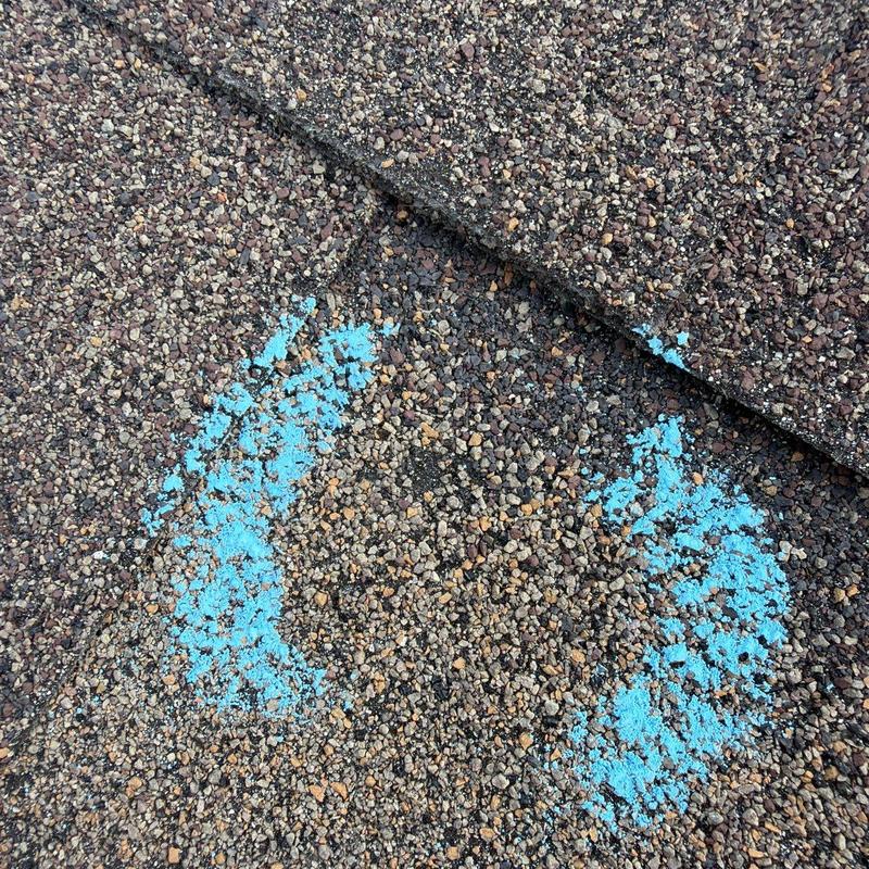 Asphalt shingles with hail damage marked in blue