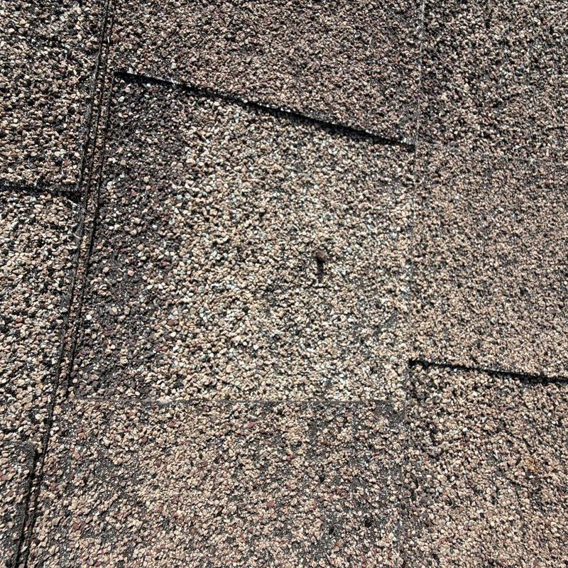 Asphalt roof shingles with visible hail damage impact