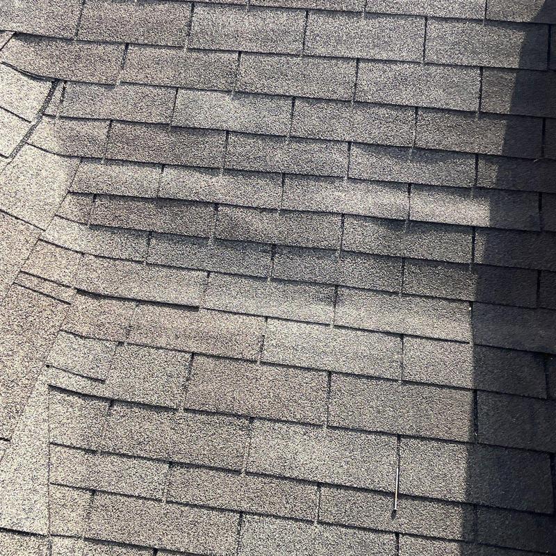 Asphalt shingles with visible hail impact damage on roof