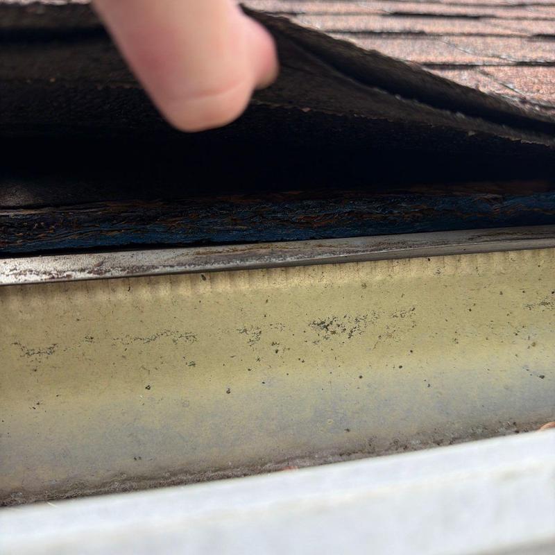 Roof shingles lifted to inspect hail damage and flashing