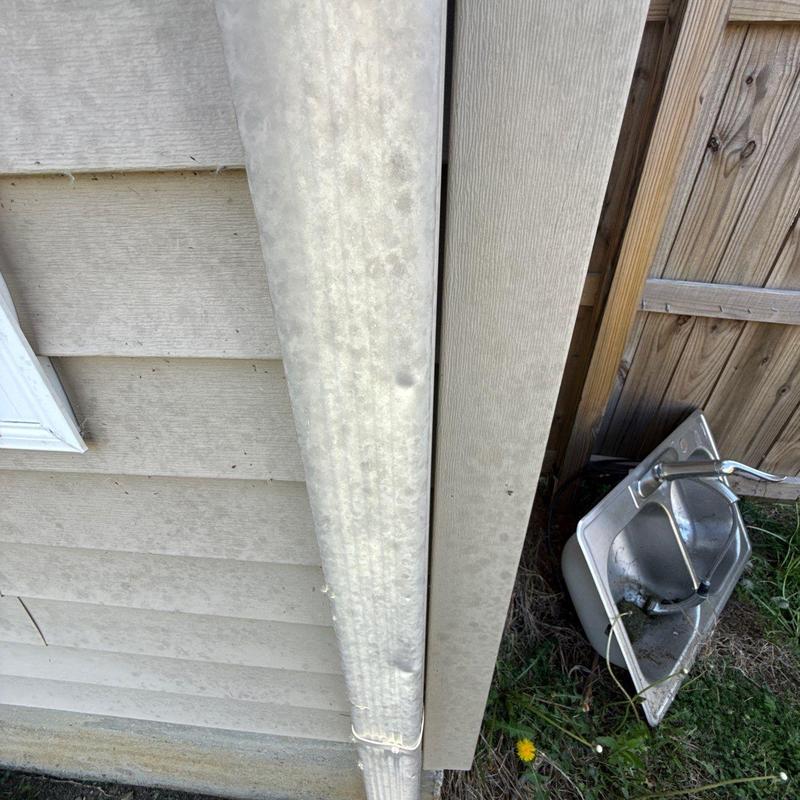 Downspout and exterior siding with visible dirt buildup
