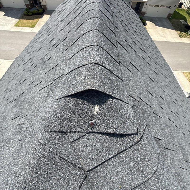 Asphalt shingles with hail damage inspection on roof ridge