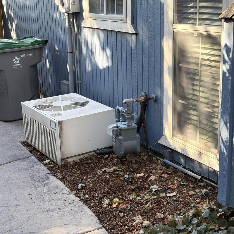 Gas valve and outdoor HVAC unit beside house wall