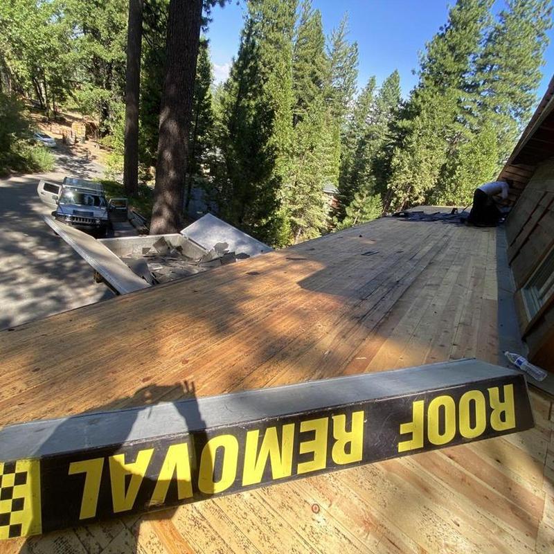 Asphalt roof decking with roof removal sign on cabin