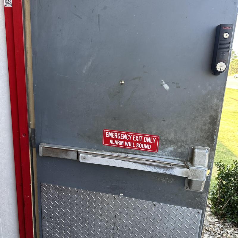 Door peep hole on commercial exit door with alarm sign Door peep hole on commercial exit door with alarm sign