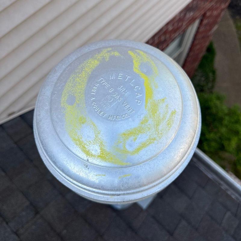 Metal vent cap with weathering marks on roof