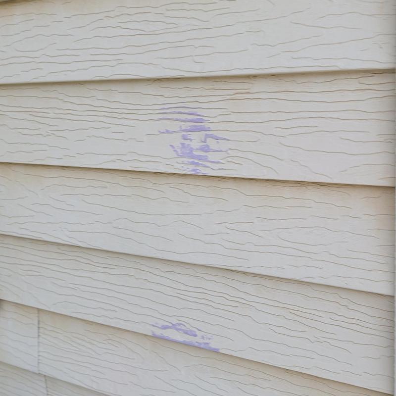 Vinyl siding with purple paint marks and texture damage