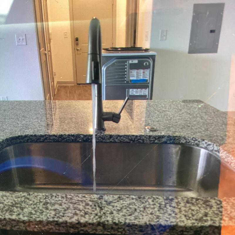 Kitchen sink faucet with running water and granite countertop