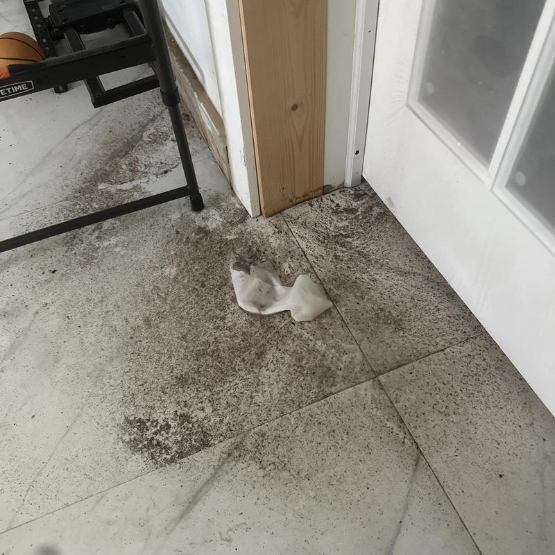Concrete floor dirt stains near door frame and wall baseboard