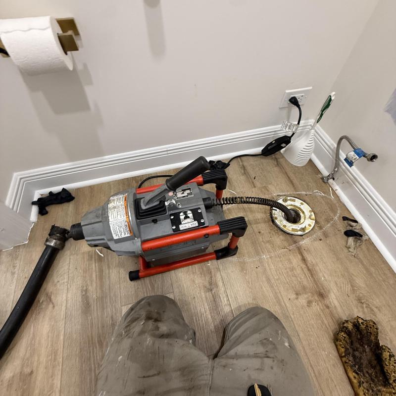 Toilet drain auger machine in bathroom floor opening