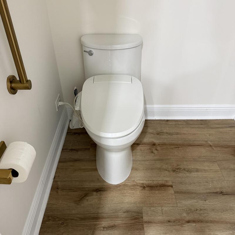 Toilet with electronic bidet seat in bathroom corner