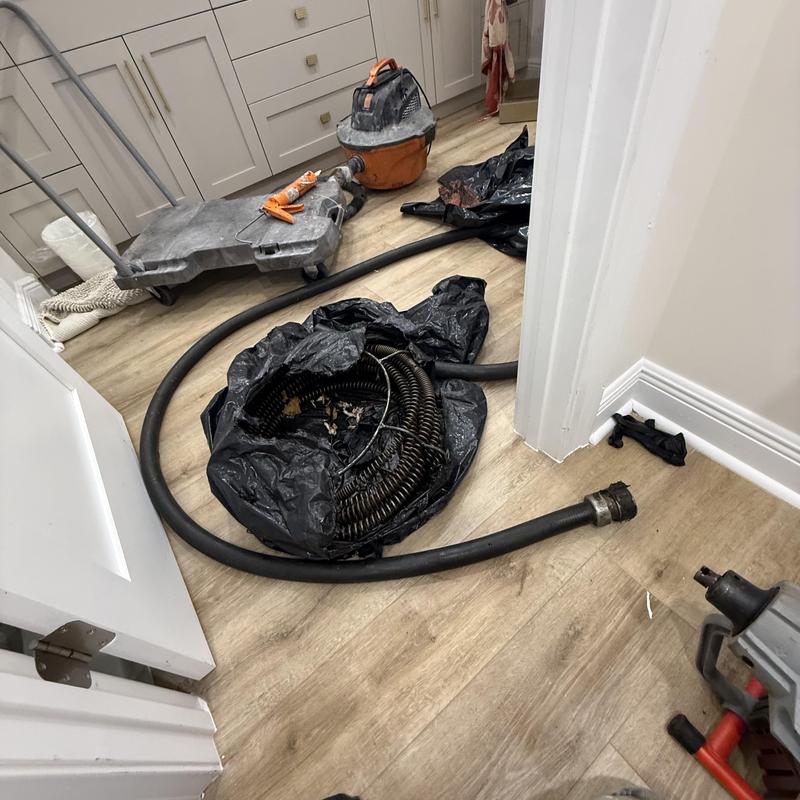 Drain cleaning hose and vacuum equipment on floor