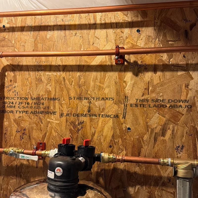 Type L copper piping with valve assembly on plywood wall