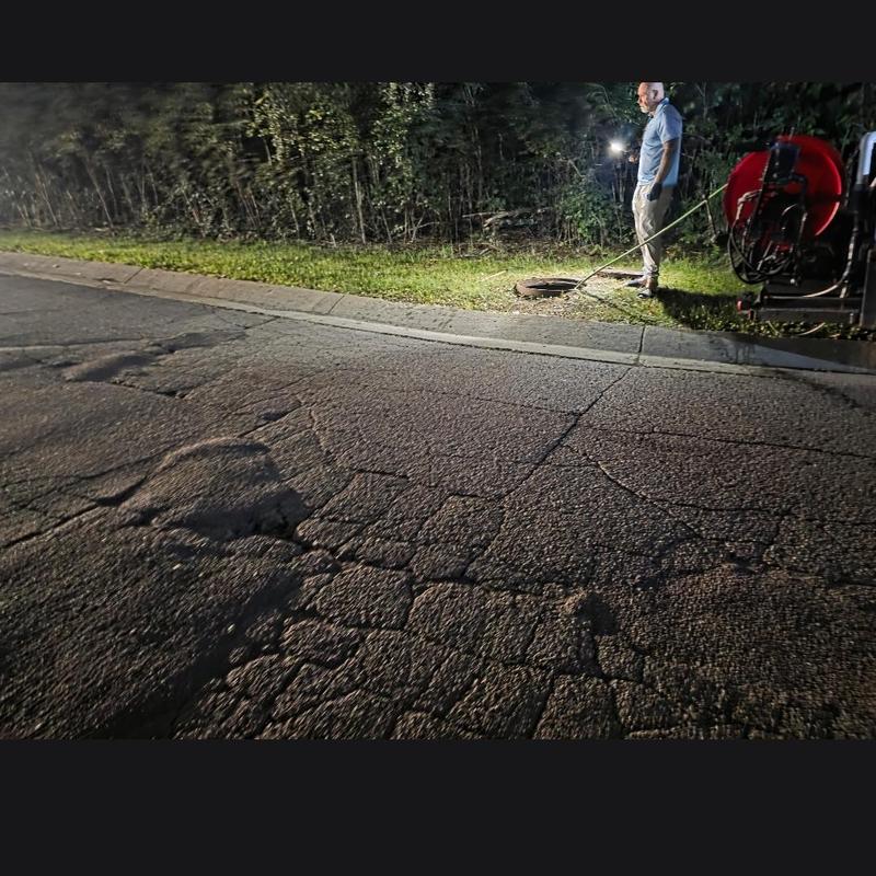 Manhole sewer line jetting clearing blockage at night