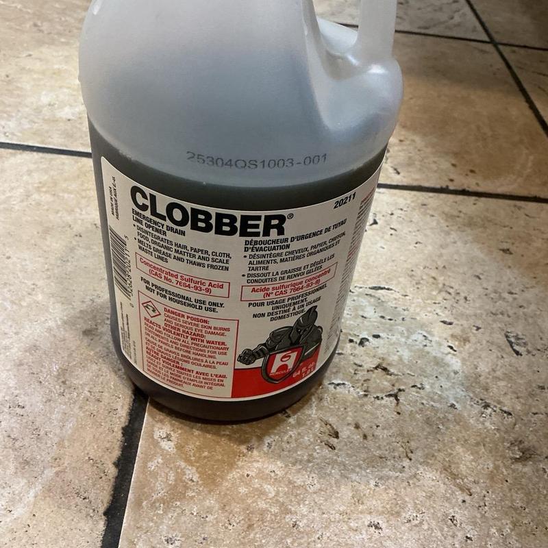 Urinal drain cleaner bottle on tiled floor