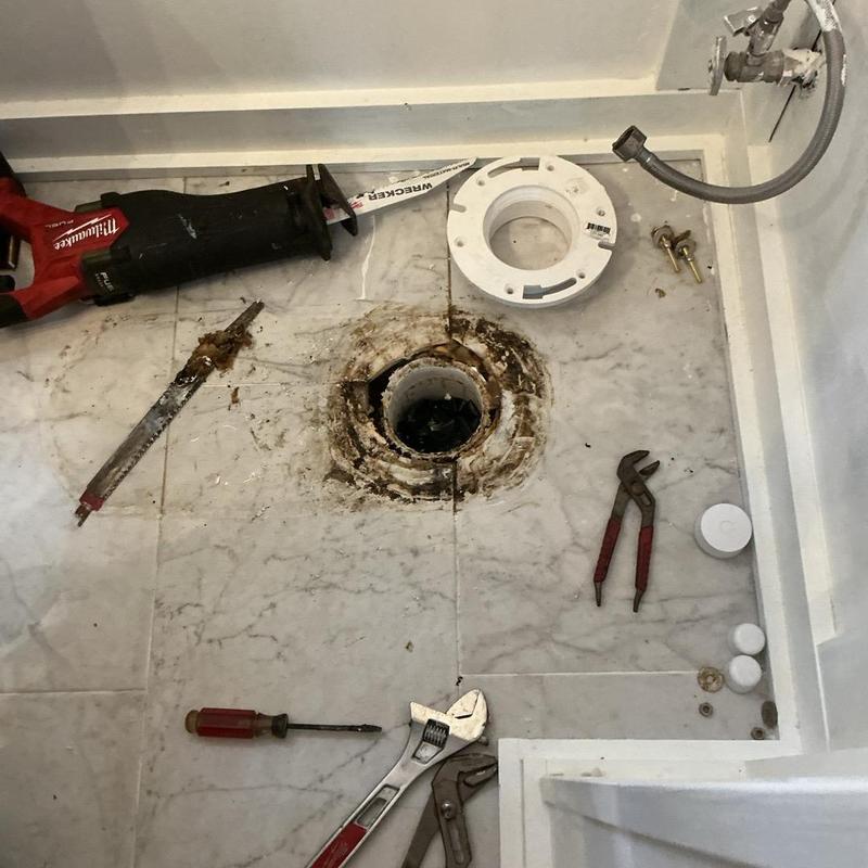 Toilet flange repair with plumbing tools on floor