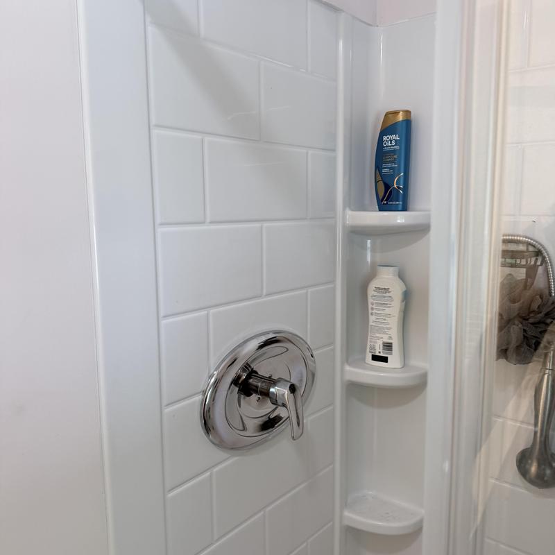 Shower valve with white tiled wall and shelves