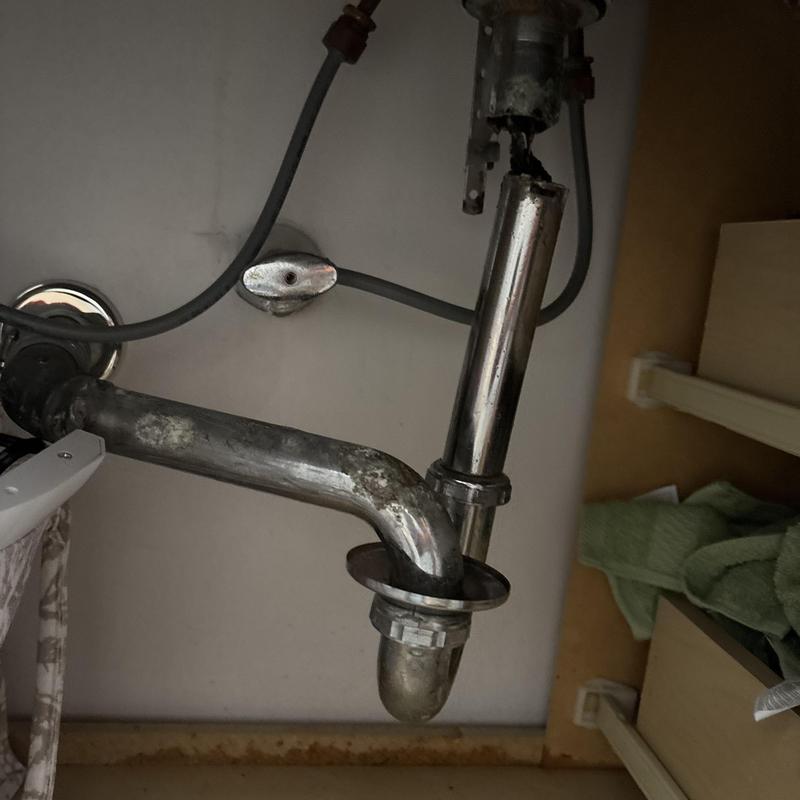 Sink drain and metal P-trap plumbing under cabinet