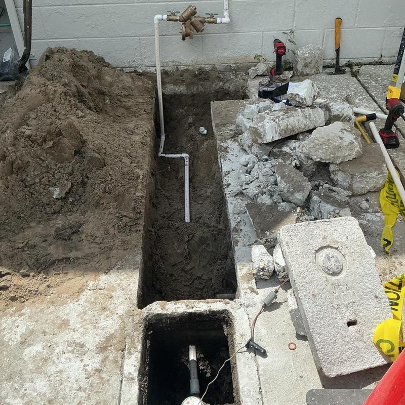 Backflow preventer installation with exposed piping and trench