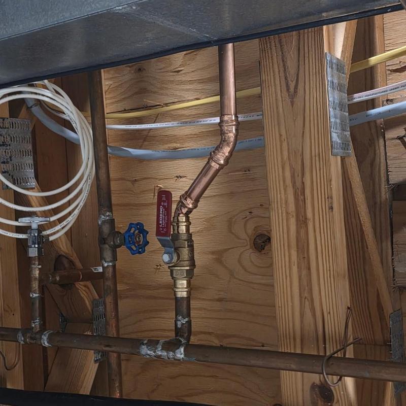 Ball valve plumbing with copper piping in basement wall