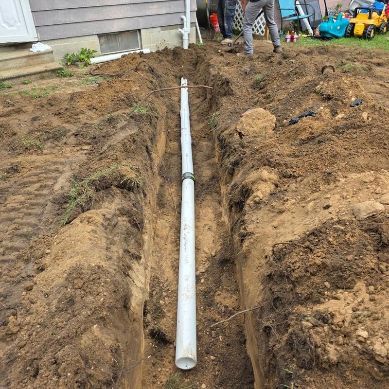 Sewer pipe installation in trench beside house exterior