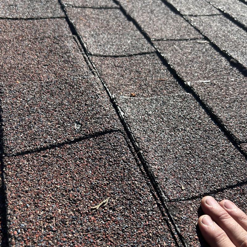 Asphalt shingles close-up with visible gaps during roof inspection