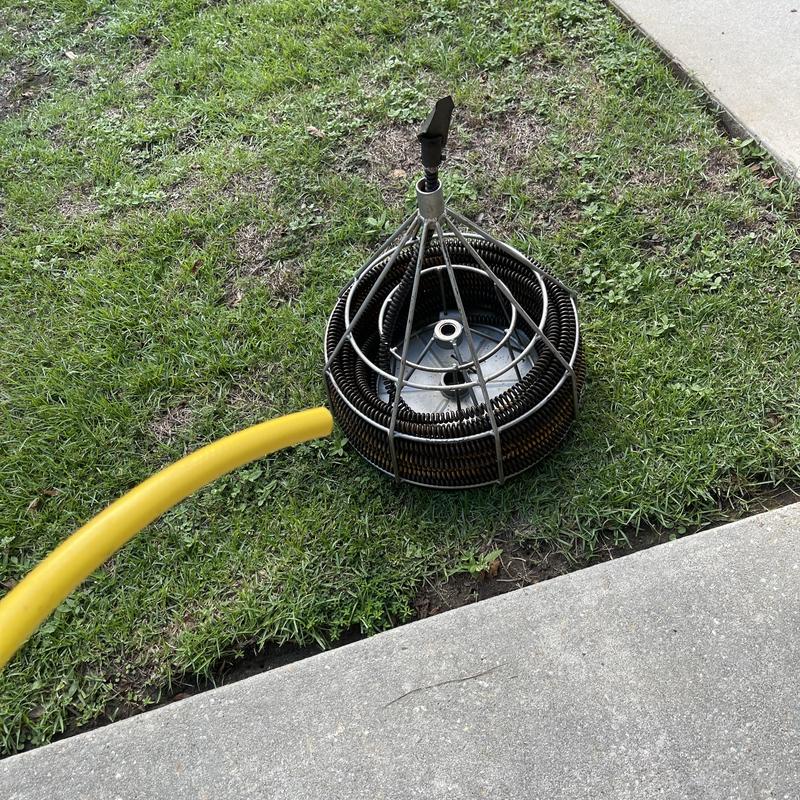 Drain cleaning snake tool with yellow hose on grass Drain cleaning snake tool with yellow hose on grass