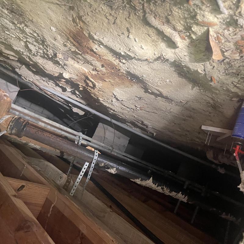 Cast iron drain pipe with metal supports in crawlspace Cast iron drain pipe with metal supports in crawlspace