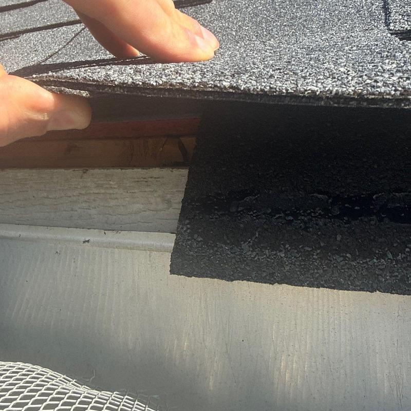 Asphalt roof shingle lifted to inspect damage in Brentwood