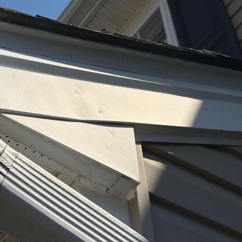 Vinyl soffit with hail damage on residential roof trim