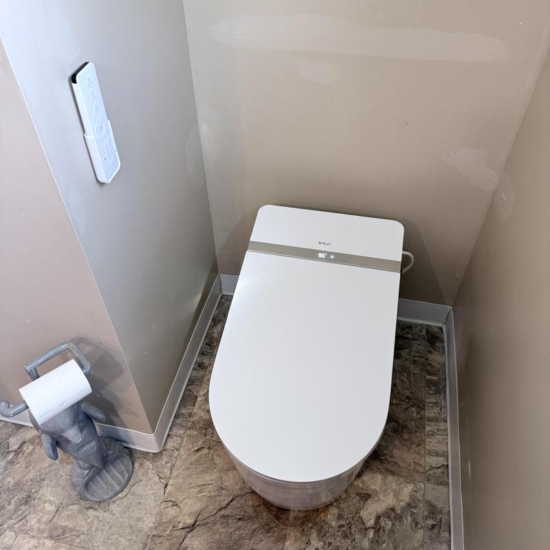 Smart toilet with remote control in bathroom corner Smart toilet with remote control in bathroom corner