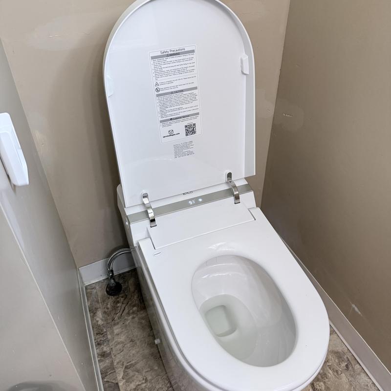 Smart toilet with open lid in bathroom corner Smart toilet with open lid in bathroom corner