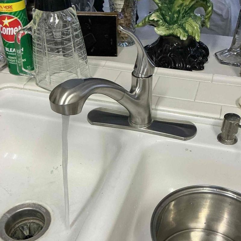 Kitchen faucet with water flow installed over white sink Kitchen faucet with water flow installed over white sink