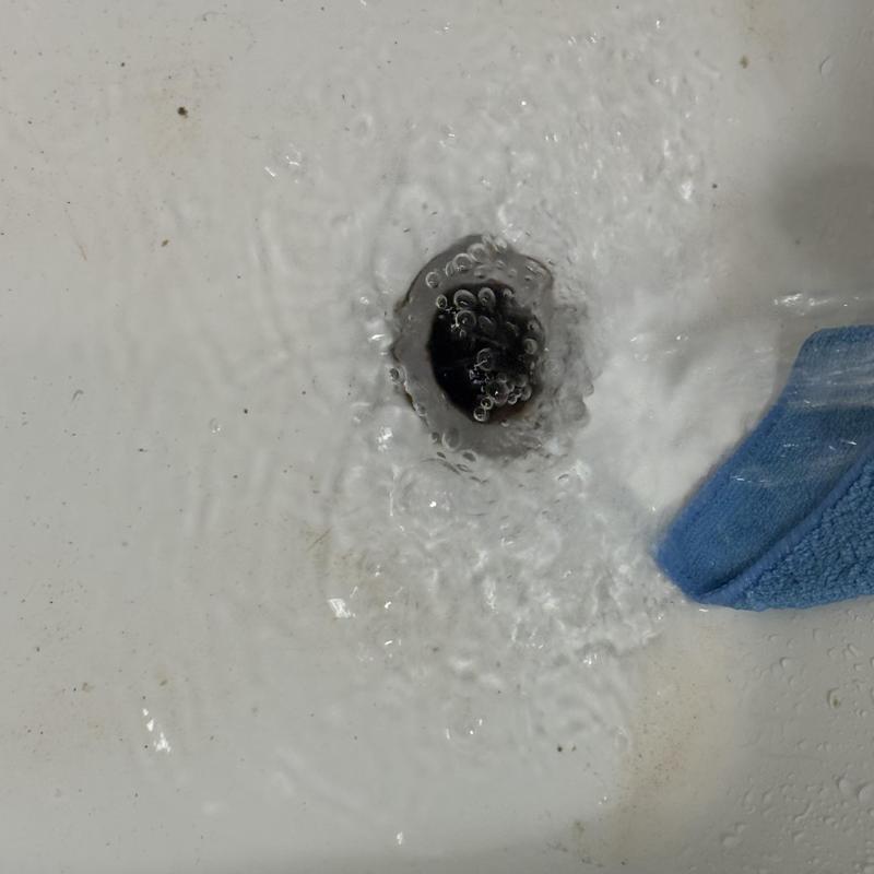 Bathtub drain clearing with water flow and towel nearby Bathtub drain clearing with water flow and towel nearby