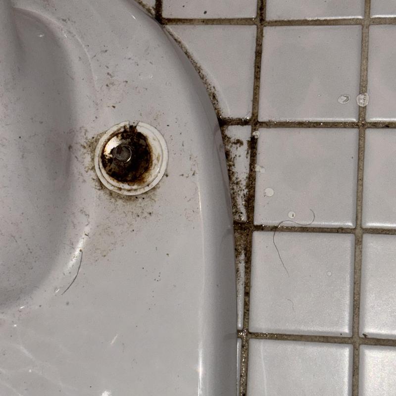 Toilet base with rust and dirt on tile grout Toilet base with rust and dirt on tile grout