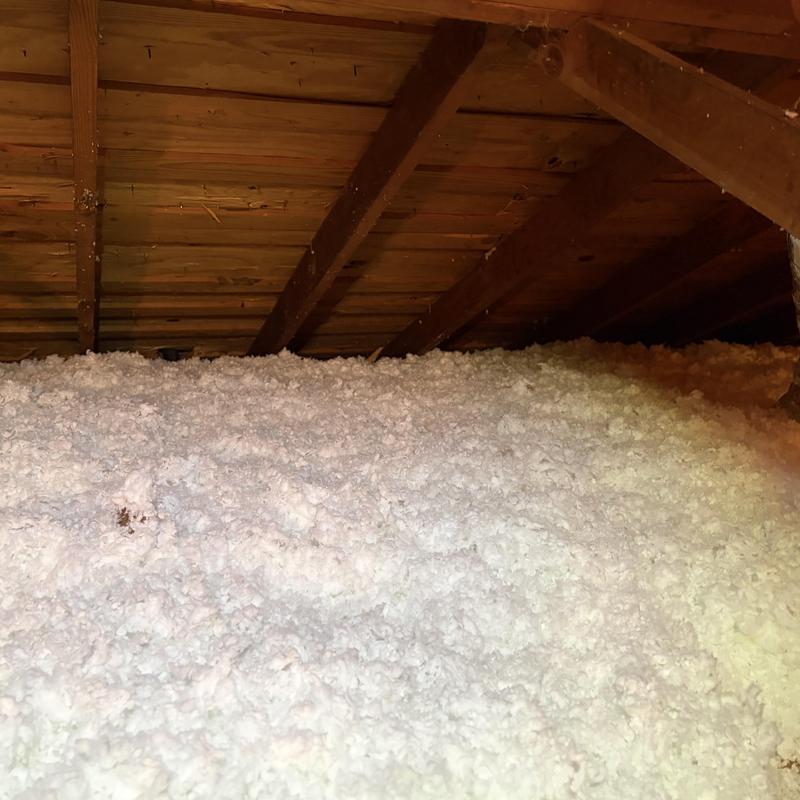 Attic loose-fill insulation installed beneath wooden rafters Attic loose-fill insulation installed beneath wooden rafters