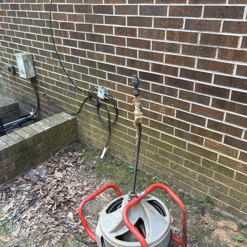 Main sewer line auger with red handles near brick wall Main sewer line auger with red handles near brick wall