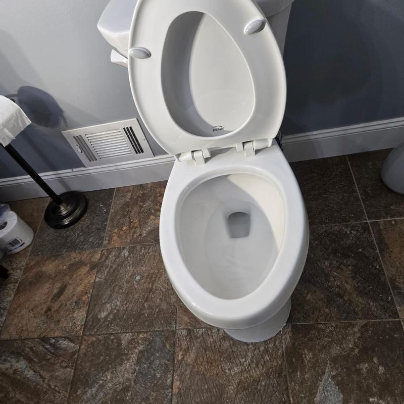 Toilet with open lid on bathroom floor tiles Toilet with open lid on bathroom floor tiles