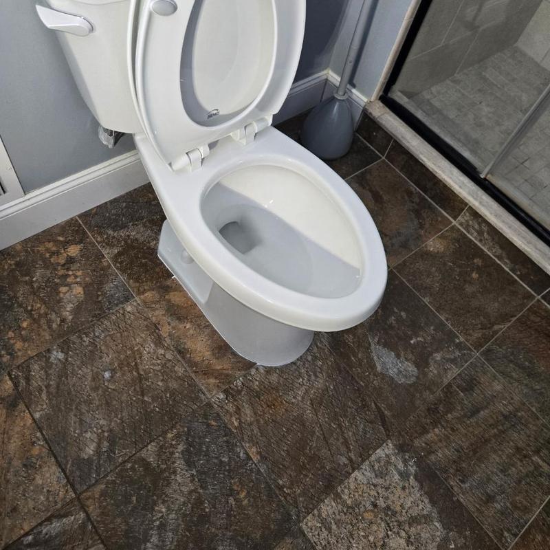 Toilet bowl with open lid on tiled bathroom floor Toilet bowl with open lid on tiled bathroom floor