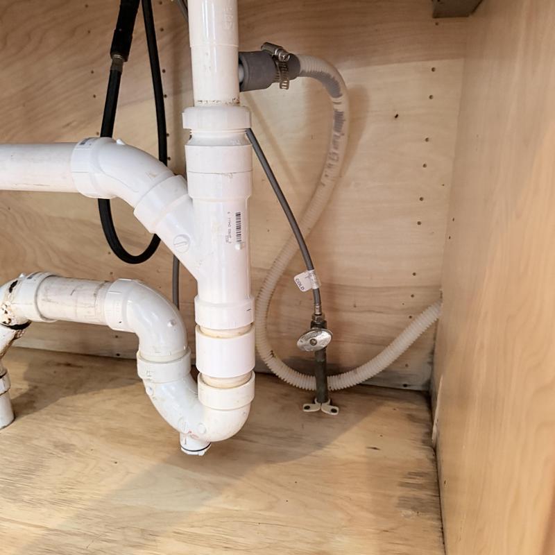 PVC drain pipes under sink with attached water supply line