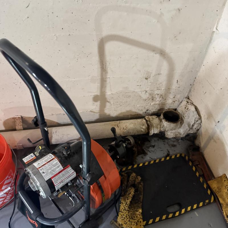 Main sewer pipe clearing with drain machine in basement