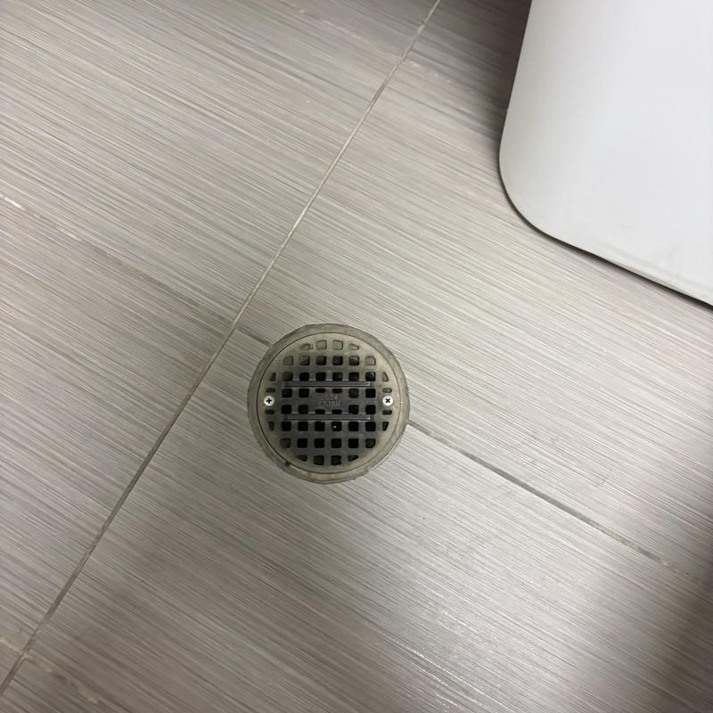 Floor drain with metal grate on tile floor Floor drain with metal grate on tile floor